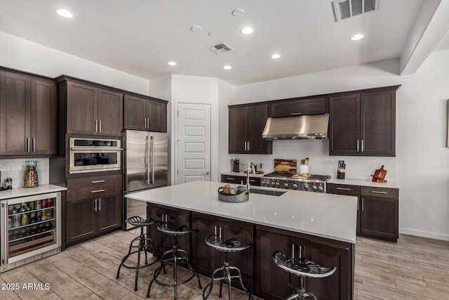 9922 E Thunderbolt Ave, Mesa, AZ 85212 - kitchen featuring beverage cooler, stainless steel appliances, under cabinet range hood, light wood finished floors, and tasteful backsplash