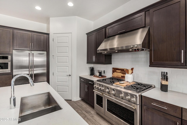 9922 E Thunderbolt Ave, Mesa, AZ 85212 - kitchen with under cabinet range hood, premium appliances, a sink, light countertops, and dark brown cabinets