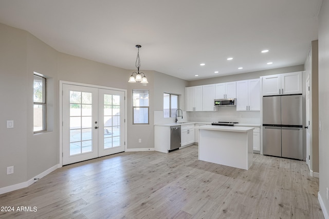 kitchen featuring pendant lighting, appliances with stainless steel finishes, light wood-type flooring, and white cabinets