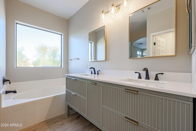 bathroom with vanity, hardwood / wood-style floors, and a relaxing tiled tub