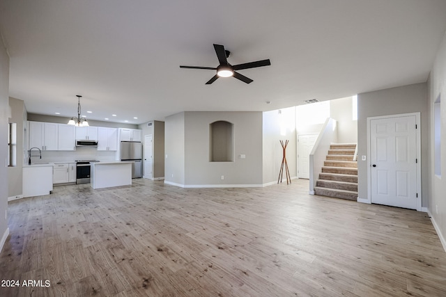 unfurnished living room featuring sink, ceiling fan with notable chandelier, and light wood-type flooring