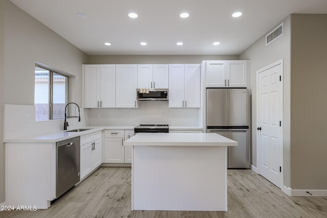 kitchen with sink, white cabinetry, stainless steel appliances, and light hardwood / wood-style floors