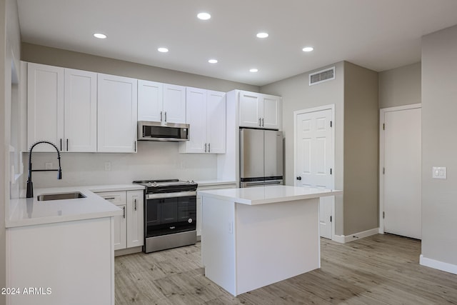 kitchen featuring a kitchen island, white cabinetry, sink, light hardwood / wood-style floors, and stainless steel appliances