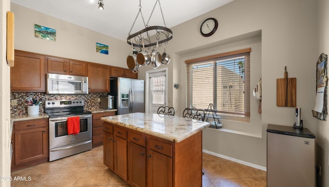1910 E Citation Ln, Tempe, AZ 85284 - kitchen featuring stainless steel appliances, light tile patterned floors, backsplash, brown cabinets, and a center island