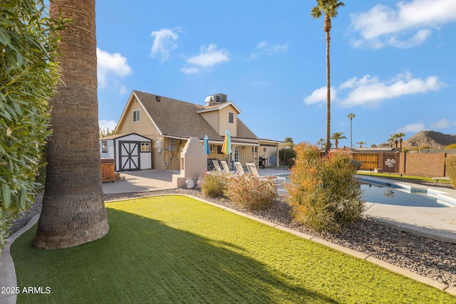 view of front facade featuring a patio area, a fenced in pool, a storage shed, and a front lawn