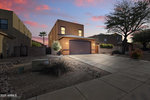 view of front of home featuring a garage, fence, concrete driveway, and stucco siding