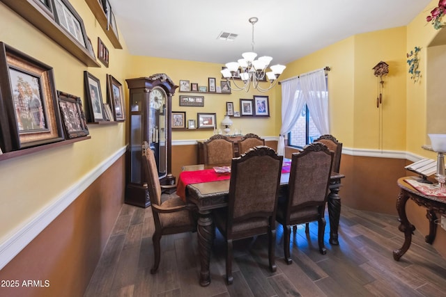 dining area featuring a wainscoted wall, a notable chandelier, dark wood-style floors, and visible vents