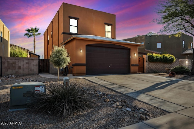 view of front of house with a gate, stucco siding, driveway, and fence