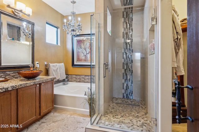 bathroom featuring a chandelier, a shower stall, vanity, and a garden tub