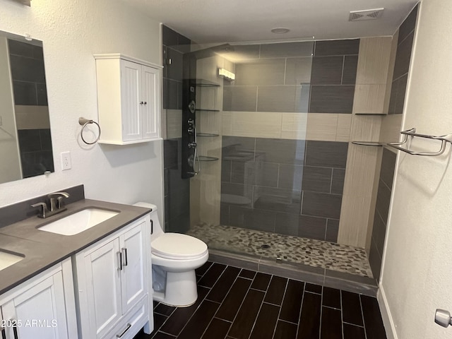 bathroom featuring vanity, toilet, and a tile shower