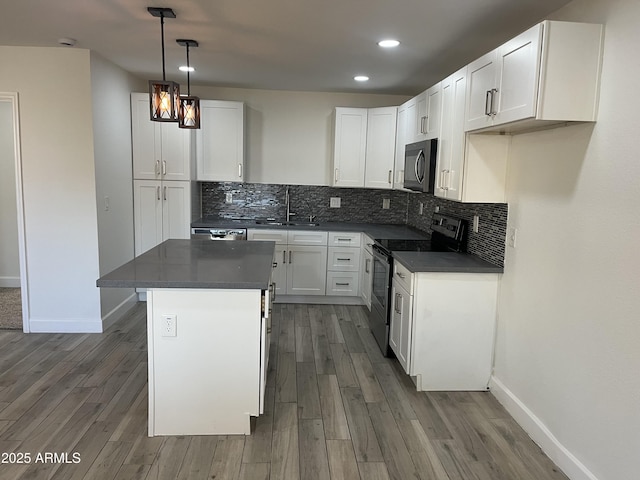 kitchen featuring appliances with stainless steel finishes, sink, pendant lighting, a center island, and white cabinetry