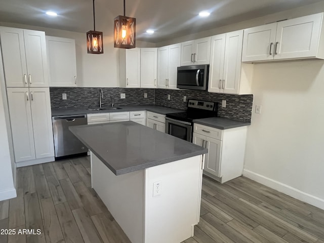 kitchen with pendant lighting, sink, a kitchen island, white cabinetry, and stainless steel appliances