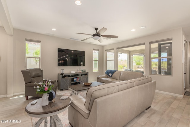 living room with a wealth of natural light, light hardwood / wood-style flooring, and ceiling fan