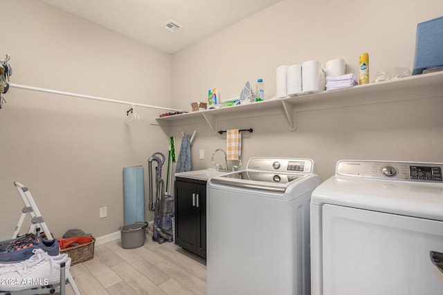 laundry area with separate washer and dryer, sink, cabinets, and light hardwood / wood-style flooring