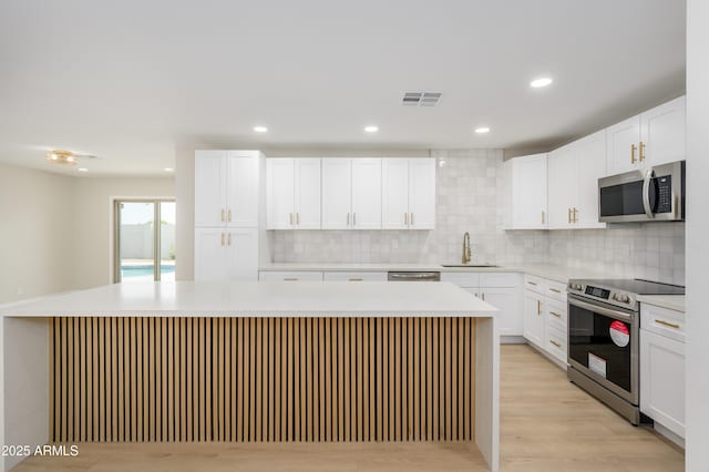 kitchen featuring visible vents, appliances with stainless steel finishes, a sink, light countertops, and light wood-style flooring