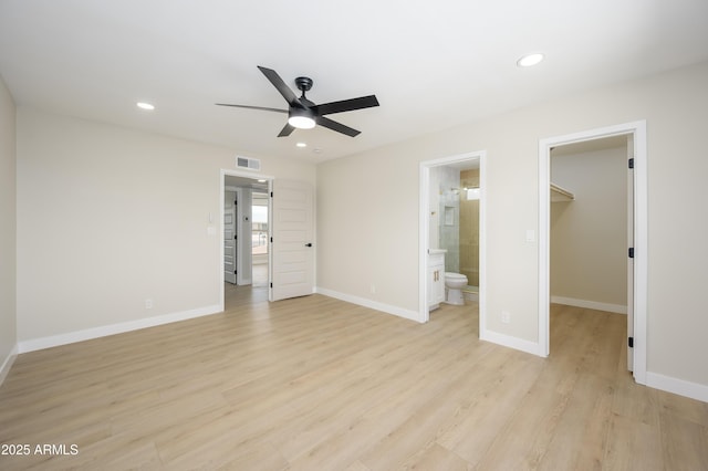 unfurnished bedroom with recessed lighting, a walk in closet, light wood finished floors, and visible vents
