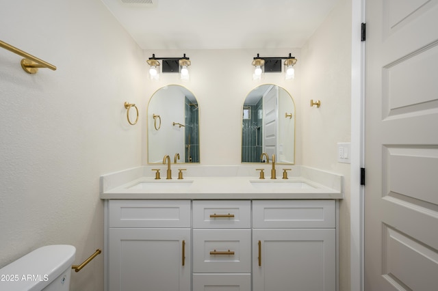 full bath with a sink, toilet, double vanity, and visible vents