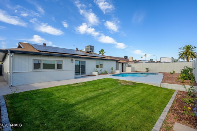 back of property with a yard, solar panels, a fenced backyard, and central air condition unit