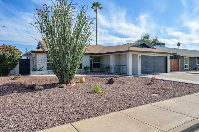 ranch-style home with fence, concrete driveway, brick siding, and a garage