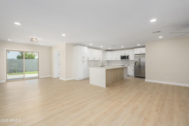 kitchen featuring light wood-style floors, light countertops, stainless steel appliances, open floor plan, and visible vents