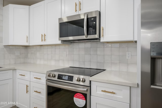 kitchen with light countertops, backsplash, stainless steel appliances, and white cabinetry