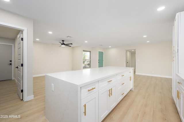 kitchen with light wood-style floors, recessed lighting, a kitchen island, and white cabinets