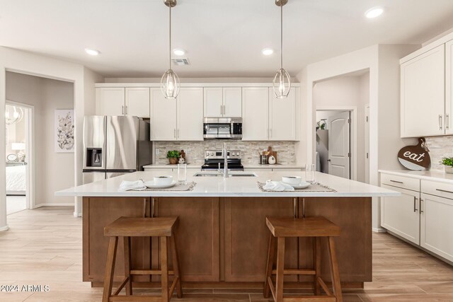 18197 W Cielo Grande Ave, Surprise, AZ 85387 - kitchen with a kitchen island with sink, appliances with stainless steel finishes, and light hardwood / wood-style flooring