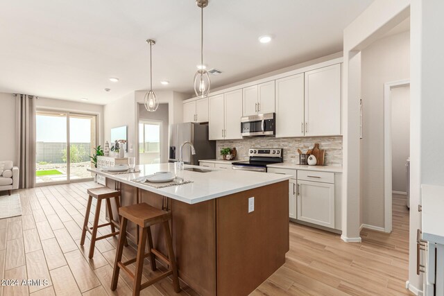 18197 W Cielo Grande Ave, Surprise, AZ 85387 - kitchen featuring a center island with sink, light wood-type flooring, white cabinetry, appliances with stainless steel finishes, and hanging light fixtures