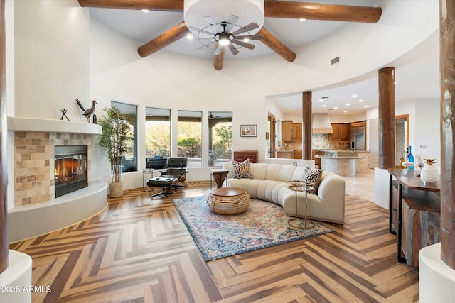 living room with a high ceiling, light parquet flooring, beam ceiling, and ceiling fan