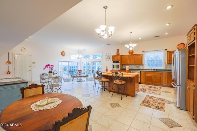 kitchen featuring appliances with stainless steel finishes, a breakfast bar, tasteful backsplash, a center island, and a notable chandelier