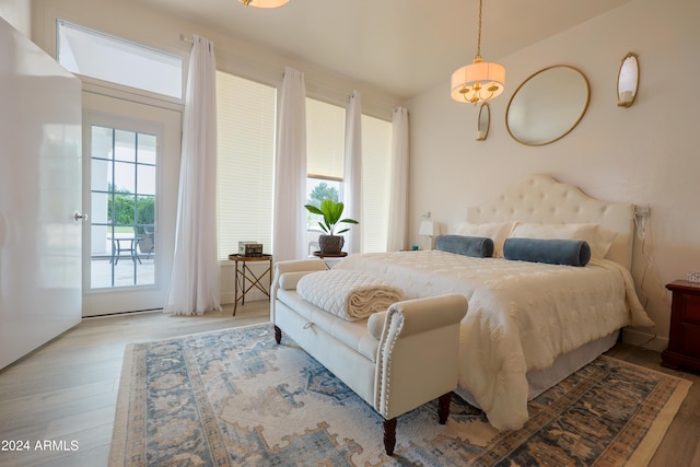 bedroom featuring light hardwood / wood-style floors, access to exterior, and a notable chandelier