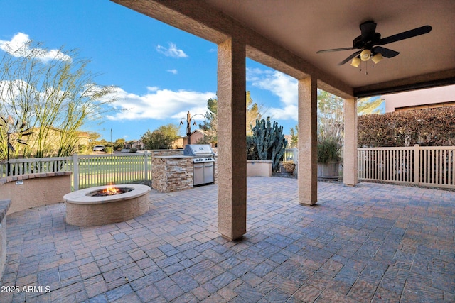 view of patio featuring a ceiling fan, a grill, fence, exterior kitchen, and a fire pit