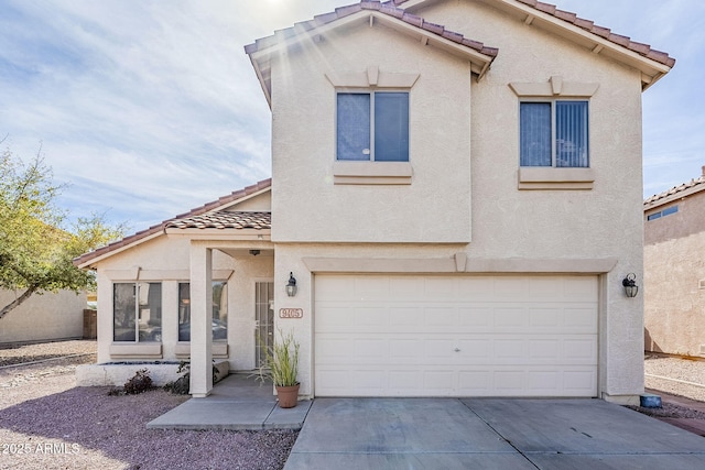 view of front of property featuring a garage, a tiled roof, driveway, and stucco siding