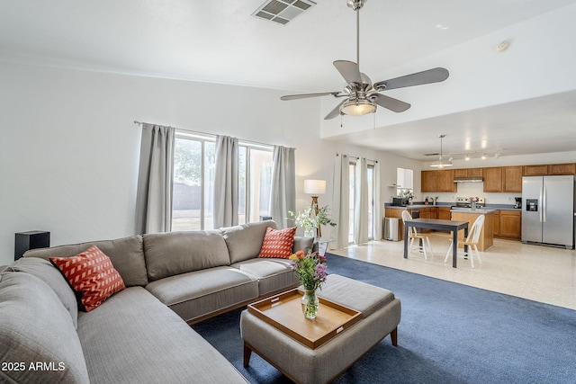 living area featuring ceiling fan, rail lighting, visible vents, and a healthy amount of sunlight