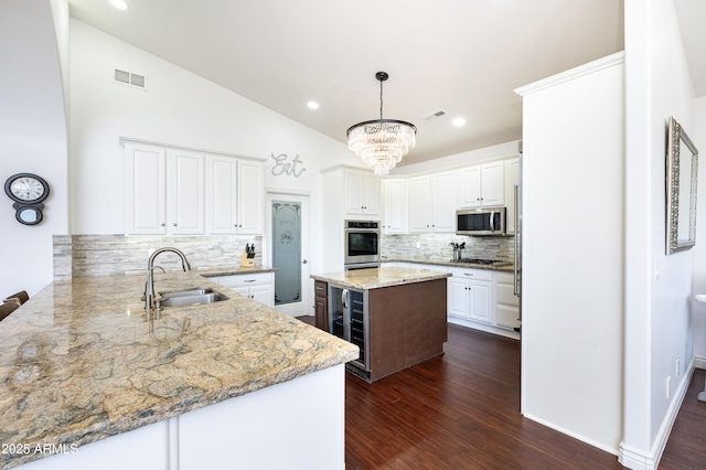 kitchen featuring lofted ceiling, stainless steel appliances, dark wood-type flooring, a sink, and visible vents