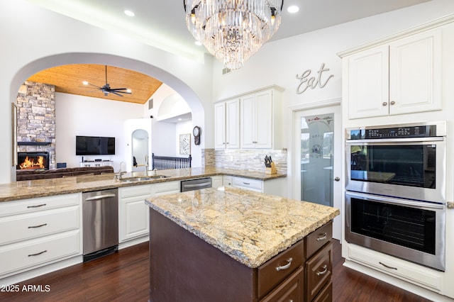 kitchen with light stone counters, stainless steel appliances, decorative backsplash, wood ceiling, and open floor plan