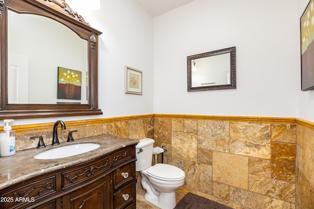 bathroom featuring wainscoting, tile walls, toilet, and vanity