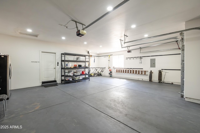 garage featuring a garage door opener, freestanding refrigerator, electric panel, and recessed lighting