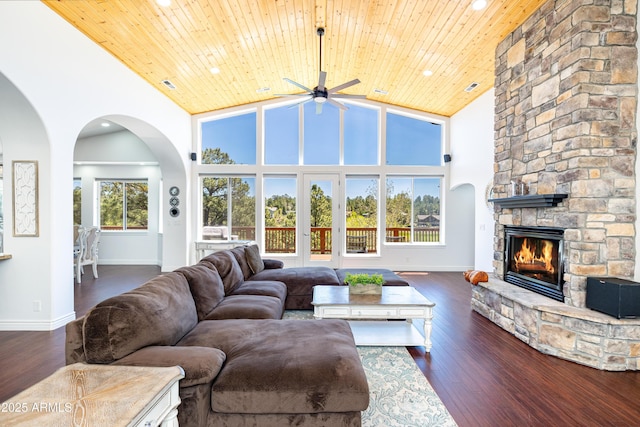 living area featuring wooden ceiling, dark wood-style floors, high vaulted ceiling, and a stone fireplace