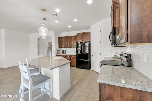 4279 N Spyglass Dr, Florence, AZ 85132 - kitchen featuring a sink, decorative backsplash, a kitchen breakfast bar, black appliances, and visible vents