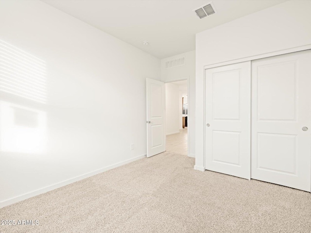 unfurnished bedroom with light carpet and a closet