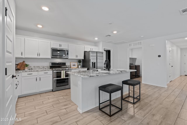 654 E Buckingham Ave, Gilbert, AZ 85297 - kitchen featuring appliances with stainless steel finishes, wood tiled floors, recessed lighting, white cabinetry, and a center island with sink