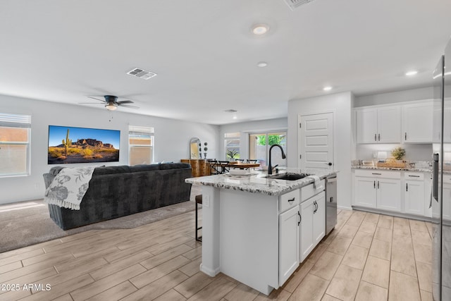 654 E Buckingham Ave, Gilbert, AZ 85297 - kitchen featuring wood finish floors, open floor plan, light stone countertops, stainless steel dishwasher, and white cabinetry