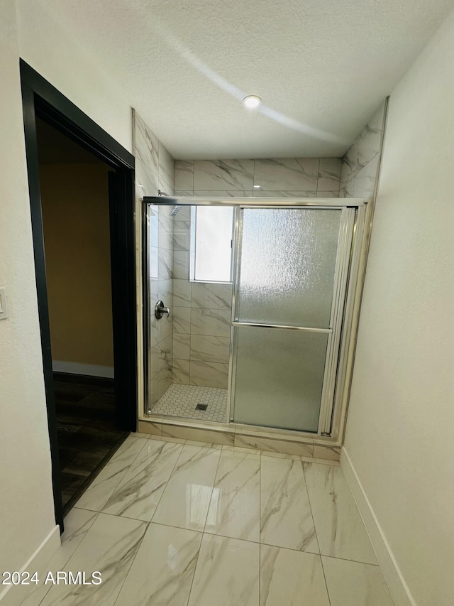 bathroom featuring an enclosed shower and a textured ceiling