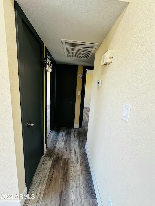 hallway featuring dark wood-type flooring and a textured ceiling