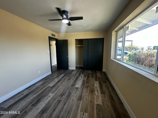 unfurnished bedroom featuring ceiling fan, dark hardwood / wood-style flooring, and a closet