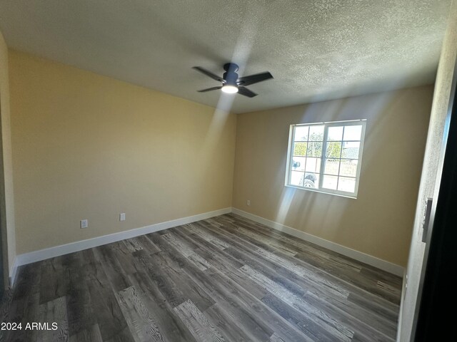 spare room with a textured ceiling, dark hardwood / wood-style flooring, and ceiling fan