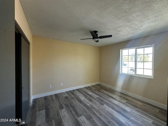 unfurnished room with a textured ceiling, ceiling fan, and dark wood-type flooring