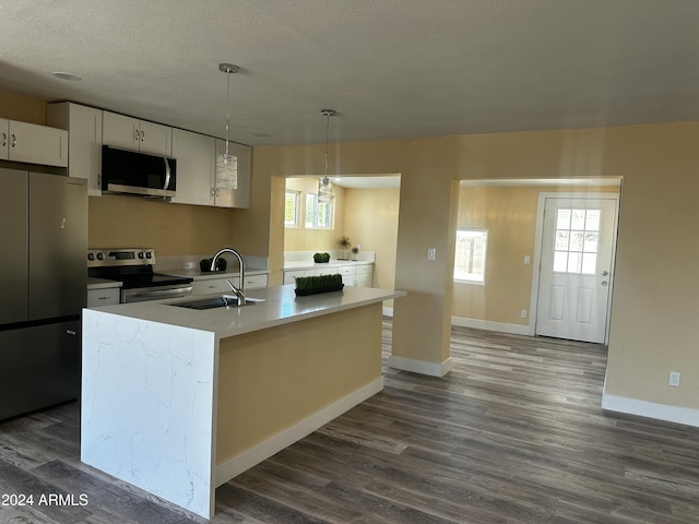 kitchen with sink, hanging light fixtures, a center island with sink, white cabinets, and appliances with stainless steel finishes