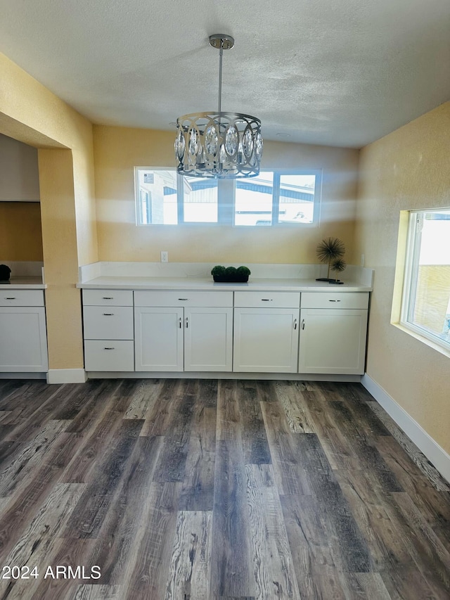 unfurnished dining area with dark hardwood / wood-style flooring, plenty of natural light, and a textured ceiling